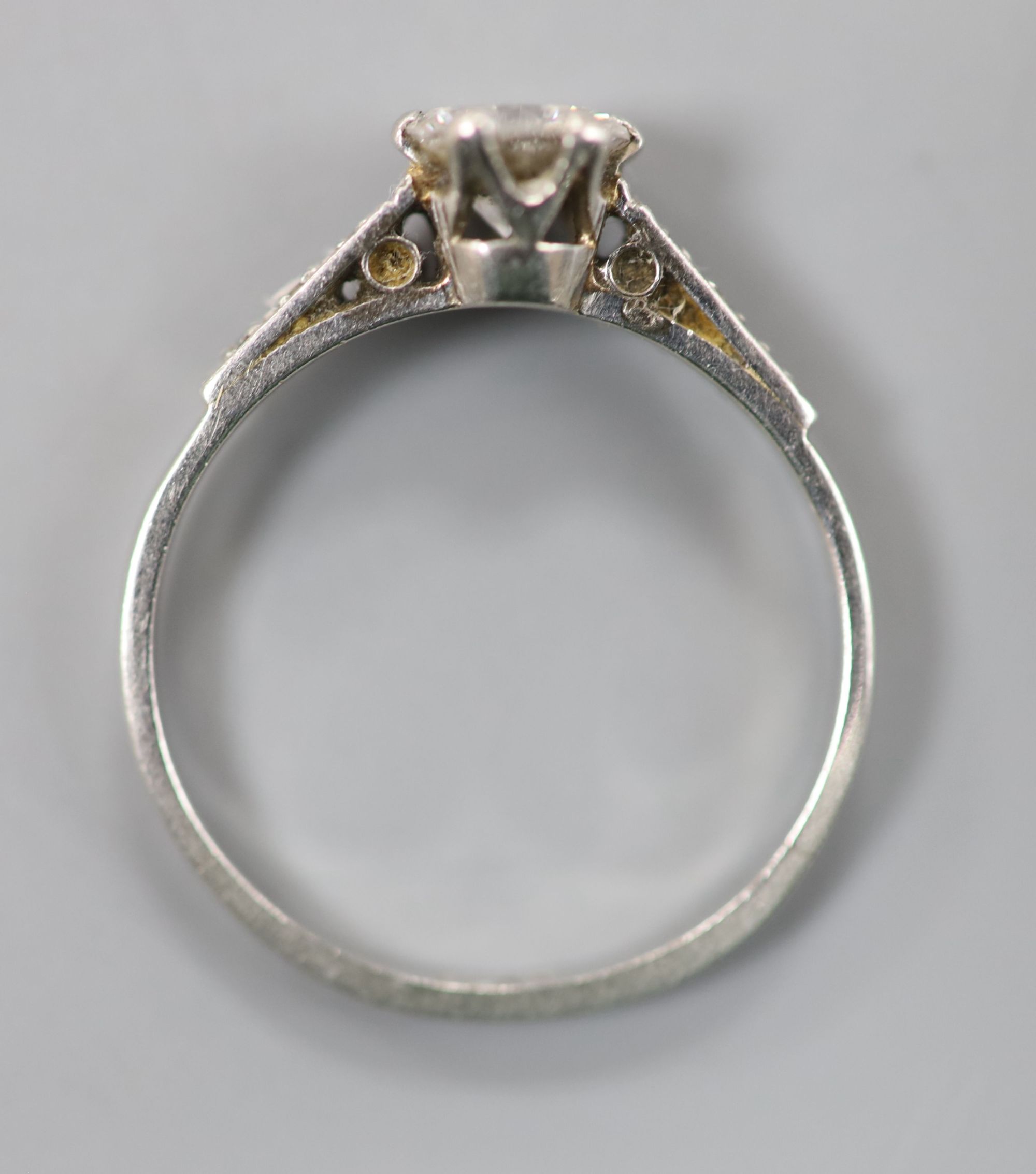 A white metal (stamped plat) platinum and single stone diamond ring, with diamond set shoulders, size M, gross 2.4 grams,